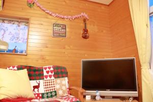 a living room with a flat screen tv and a couch at 陽のあたる宿 サンセットパーム in Oshima