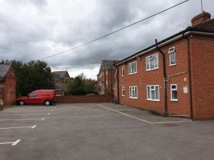 uma carrinha vermelha estacionada num parque de estacionamento ao lado de um edifício de tijolos em Tower House Hotel em Reading