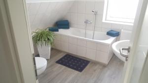 a bathroom with a tub and a toilet and a sink at Ferienwohnung 1 "Ferienhaus Seibert" in Ellerdorf +13 photos
