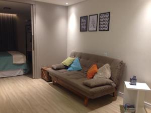 uma sala de estar com um sofá com almofadas em Charmoso e Confortável em Brasília