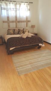 a bed in a bedroom with a window and a rug at 91 Da Gama Beach House in Cape St Francis +13 photos