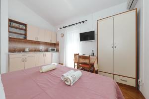 a bedroom with a pink bed with towels on it at Apartments Vedrana in Biograd na Moru
