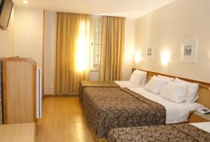 a hotel room with two beds and a window at Hotel Regina Rio de Janeiro in Rio de Janeiro