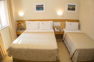 a hotel room with two beds and a phone at Hotel Regina Rio de Janeiro in Rio de Janeiro