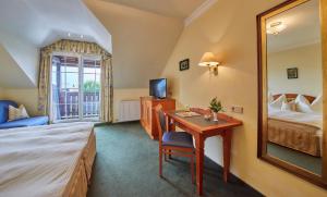 um quarto de hotel com uma secretária, uma cama e um espelho em Hotel Die Pflegerbrücke em Salzburgo
