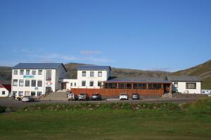 een wit gebouw met auto's geparkeerd op een parkeerplaats bij Hotel Breidavik in Breiðavík