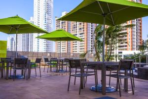 un grupo de mesas y sillas con sombrillas verdes en Ramada Plaza by Wyndham Panama Punta Pacifica, en Panamá