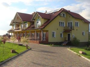 a large yellow house with a brick driveway at Hotel Pod Jaskółką in Kołomań