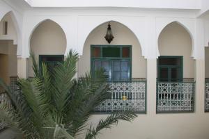 a building with arches and a balcony with a plant at Riad Orange in Marrakesh