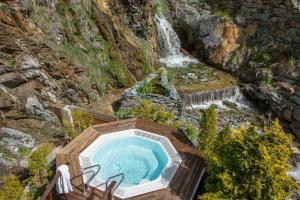an outdoor hot tub in front of a waterfall at Hotel Sonne in Zermatt