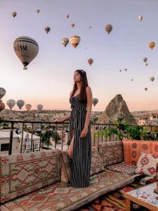 a woman standing on a balcony with hot air balloons at Göreme Art Stone in Göreme