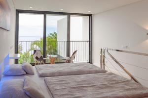 a bedroom with two beds and a balcony at Quinta Golfinho in Arco da Calheta +147 photos
