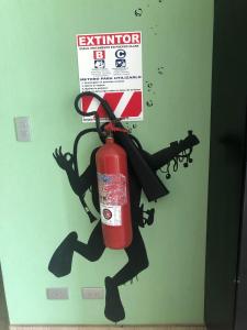a fire extinguisher sign on a door with a person holding a gun at Room2Board Hostel and Surf School in Jacó