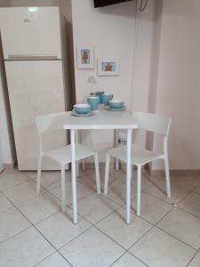 een witte tafel met 2 stoelen en een witte koelkast bij Casa Mia Miniapartment in Riposto