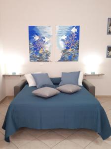 een slaapkamer met een blauw bed en 2 schilderijen aan de muur bij Casa Mia Miniapartment in Riposto