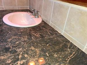 a bathroom with a pink sink on a marble floor at Reef Winds Villa in Runaway Bay +17 photos