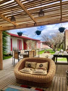 un sofá de mimbre sentado bajo una pérgola en una terraza de madera en Wild Hostel, en Puerto Natales