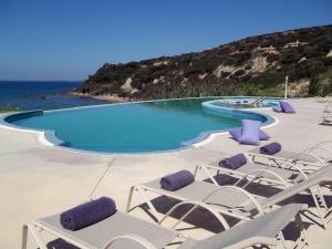 スカフィディアにあるMare Dei Suites Hotel Ionian Resortのラウンジチェア付きのスイミングプールと海