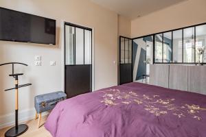 a bedroom with a purple bed and a flat screen tv at Le Fuseau de Reims in Reims