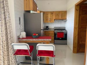 uma cozinha com 2 cadeiras vermelhas e um frigorífico em KSL Residence em Boca Chica