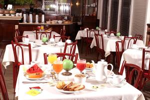 un comedor con mesas blancas con comida y bebida en Hotel Flat Bassano Vaccarini, en Ribeirão Preto