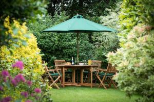 a wooden table and chairs under a green umbrella at Westgate Lodge at Dedham in Dedham