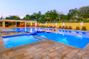 una gran piscina con sillas y agua azul en Hotel Fazenda Areia que Canta, en Brotas