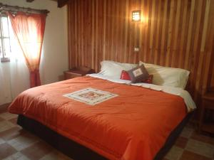 a bedroom with a large bed with an orange blanket at Cabañas Sierra Verde in Zacatlán