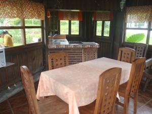 a dining room with a table and a kitchen with windows at Cabañas Sierra Verde in Zacatlán