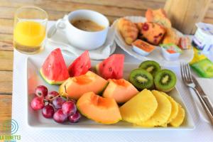 a plate of fruit on a table with a cup of coffee at Hotel-Restaurant La Dunette in Sainte-Anne