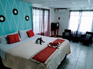 a bedroom with a large bed with red pillows at The Red Hut Inn in Belize City