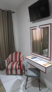a room with a chair and a desk with a mirror at Inter Park Hotel in Ponta Porã