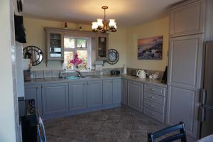 a kitchen with blue cabinets and a sink and a window at Lighthouse Cottage in Donegal