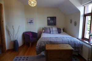 a bedroom with a bed and a blue chair at Lighthouse Cottage in Donegal