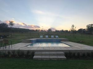 een zwembad met stoelen en een zonsondergang in een veld bij Steenkoppies estate semi self catering unit 1 in Magaliesburg