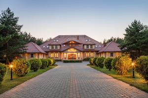 a large house with a brick driveway at Hotel - Dworek Tryumf in Księżyno