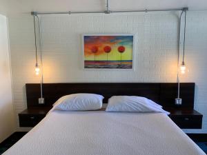 a bed with two pillows and a painting on the wall at The Sands Motel in Boulder City