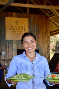 une femme détient deux assiettes de nourriture dans l'établissement Pristine Paradise Dive Resort Una Una, à Pulau Unauna