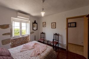 Un dormitorio con una cama y una ventana y una silla. en Casa do Lagar, en Óbidos