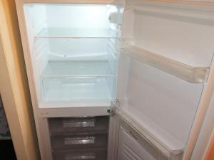 an empty refrigerator with its door open and empty shelves at Fearnhead House in Warrington