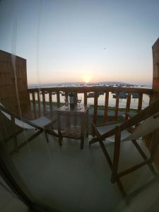 Bamboo Lodge Paracas في باراكاس: طاولة وكراسي على شرفة مع غروب الشمس