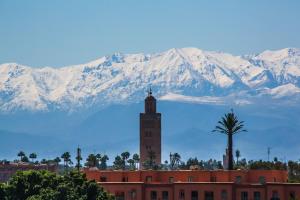 ein Gebäude mit einem Uhrturm vor einem Berg in der Unterkunft Riad Laila in Marrakesch