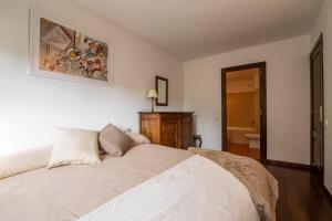 um quarto com uma cama branca e uma fotografia na parede em NOGUERA de Alma de Nieve em Baqueira-Beret