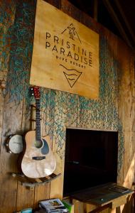 une guitare suspendue sur un mur à côté d'un panneau dans l'établissement Pristine Paradise Dive Resort Una Una, à Pulau Unauna