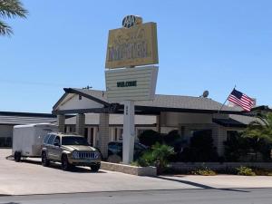 een bord voor een motel met een truck voor de deur bij The Sands Motel in Boulder City