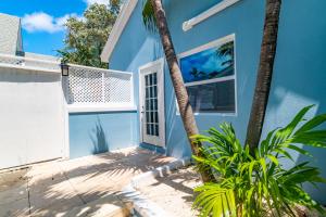 a blue house with palm trees in front of it at Saunders 3BD Beach Cottage in Nassau