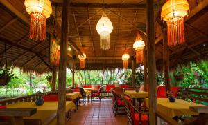 San KamphaengにあるSecret Garden Chiangmaiのテーブルと椅子、シャンデリアのあるレストラン