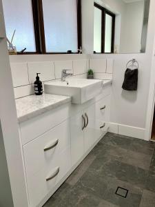cocina blanca con lavabo y espejo en Berds Nest en Emu Bay