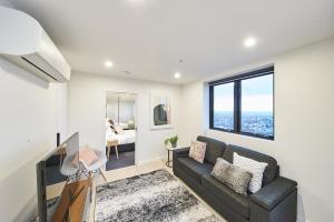 a living room with a couch and a large window at Mega Style Apartments The International in Melbourne