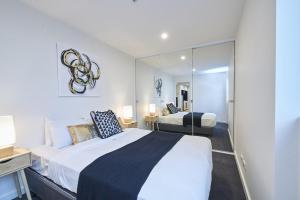 een slaapkamer met een groot bed en een spiegel bij Mega Style Apartments The International in Melbourne